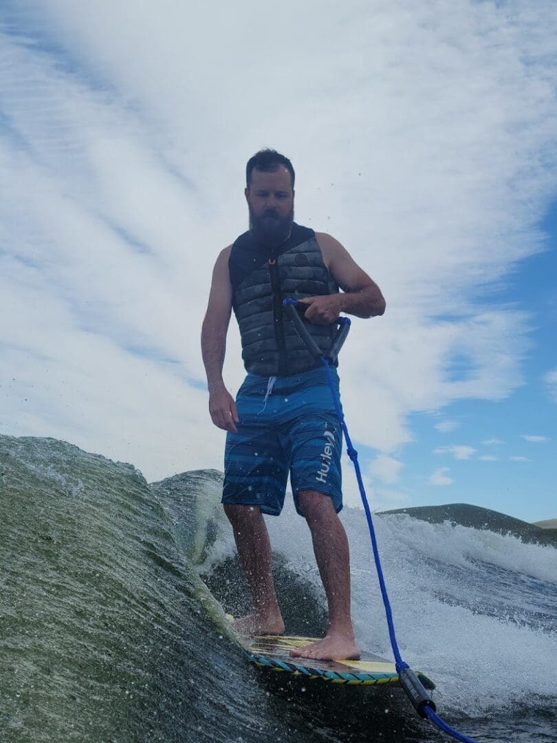 A man standing on top of a surfboard in the sand.