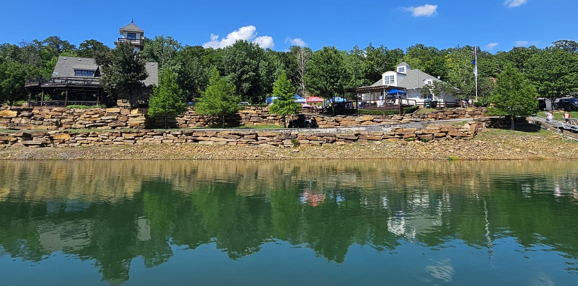 A lake with houses on the shore and trees in the background.