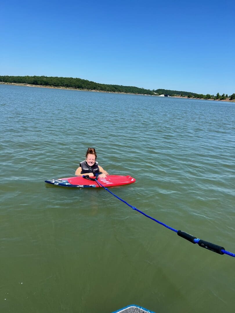 A young boy is sitting on the water with his board.